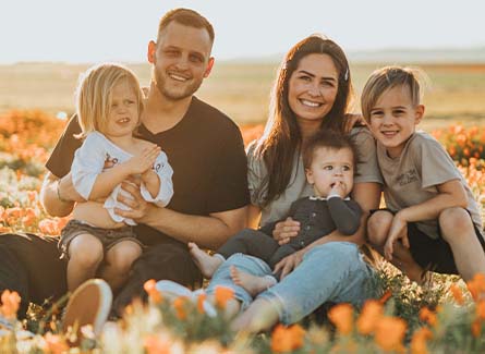 An outdoor family photo of parents with three children