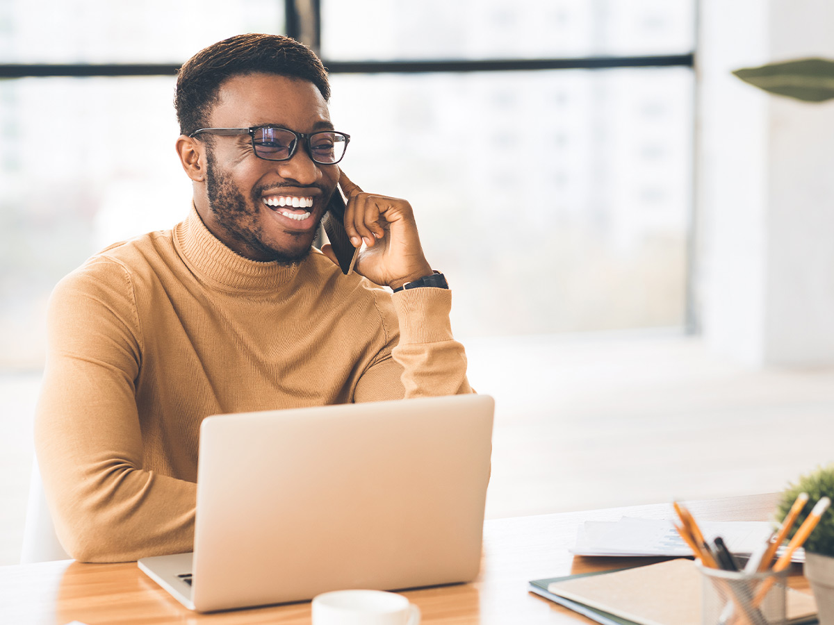 a man on the phone in front of a laptop