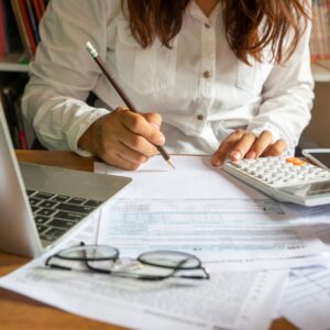 a woman looking at paperwork with a calculator