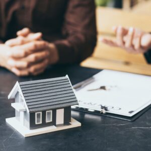 people looking at paperwork in front of a tiny model home