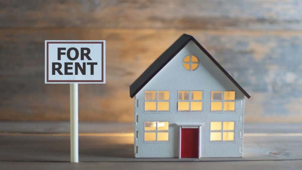 Model house with a small for rent sign next to it.