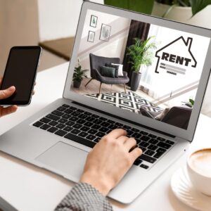 Person looking at a computer screen with a picture of a home and the word "rent".